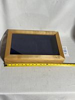 Closed wooden display box with tape measure showing length