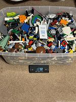 Top view of clear tub filled with assorted LEGO pieces on scale displaying 11.78 kg