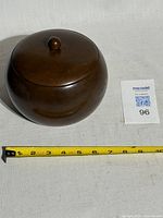 Closed wooden ice bowl next to ruler