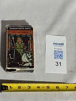 Front of tuck box showing The Chariot illustration with measuring tape for scale