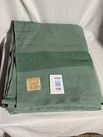 Folded reseda green blanket with label visible