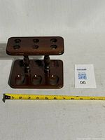 Side view showing full two-tier wooden pipe stand with measuring tape for scale