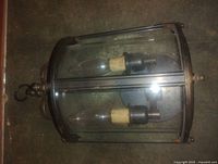 Overall view of glass and metal wall sconce showing two candelabra bulbs, glass panels, metal frame