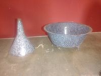 Strainer bowl and funnel full view against red wall