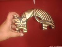 Front view of carved wooden cat showing face, arched body and stripe pattern