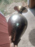 Full view of hammered metal vase held upright