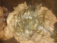 Pile of brass hanging components on paper showing loops and clip bodies