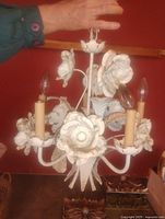 Full view of painted metal floral chandelier showing five arms, candle sleeves, and wired stem