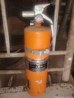 Full view of orange Pyrene fire extinguisher standing upright