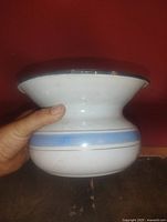 Side view of white enamel spittoon with blue band