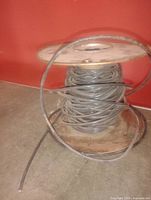 Entire spool showing coiled dark grey cable on wooden reel