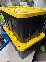 Two stacked black heavy duty storage totes with yellow lids showing overall condition and design