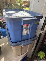 Blue tote stacked on beige tote, both with lids showing Roughneck label