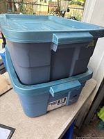 Stacked Rubbermaid Roughneck blue totes with lids showing exterior condition and labels