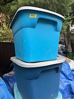 Stacked blue plastic totes with lids outdoors