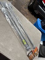 Three packaged silver curtain rods on table