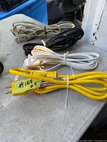Coiled yellow, white, black and beige extension cords on table