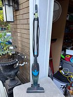 Full view of BISSELL stick vacuum upright against wall