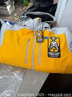 Full view of yellow and grey jacket folded with logo tag visible