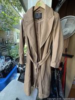 Full view of camel belted coat hanging