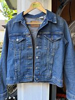 Front view of denim jacket on hanger showing overall style and button front