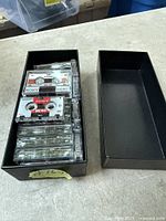 Box containing stacked Sony and TDK MC60 microcassettes with lid beside
