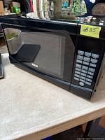 Front view of black RCA microwave showing door, window and overall exterior condition