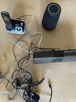 Cordless phone with base, cylindrical speaker, soundbar, cables visible