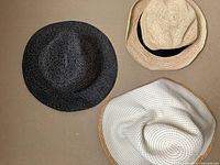 Top view of three woven sun hats showing colors and styles