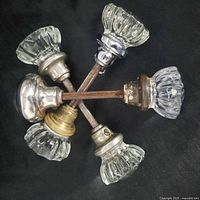 Five glass door knobs arranged star-shape showing glass heads and metal bases