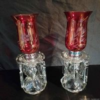 Full view of both cranberry etched hurricane lustre lamps with prisms attached