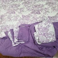 Overview of duvet, folded sheet set, and pillowcases showing floral and solid purple sides
