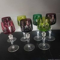 Group shot of seven multicolour cut-to-clear goblets on black surface