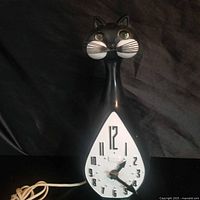 Full view of black cat wall clock showing shape and cord