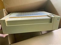 Front angled view of printer in box showing Apple logo and general condition