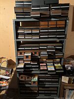 Full view of metal shelving unit with multiple drawers containing audio cassette tapes