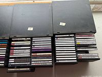 Two black plastic CD storage boxes labeled 3 and 4 with rows of jewel case CDs visible