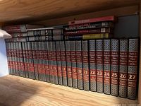 Full row of 27 hardcover Funk & Wagnalls New Encyclopedia volumes on shelf