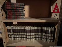 Row of Funk & Wagnalls volumes 3–29 and stacked red-black reference books