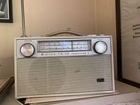 Front view of Hitachi Transistor 9 FM/AM portable radio showing tuning scale, knobs, speaker grille and handle