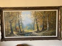 Front view of signed oil landscape in ornate carved frame