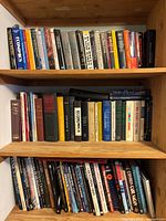 Three shelves of assorted hardcover and paperback science, economics and reference books