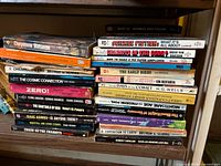 Stack of paperbacks and hardcovers on shelf showing titles like Cheyenne Autumn, Science Fiction: What It’s All About, Chariots of the Gods, The Cosmic Connection