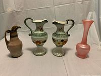 Group shot of beige ceramic ewer, two green porcelain floral ewers and pink frosted glass bud vase