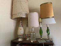 All four vintage mid-century table lamps with shades displayed on shelf