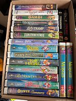 Box of stacked Disney VHS titles including The Prince of Egypt, Bambi, Lady and the Tramp, The Little Mermaid, etc.