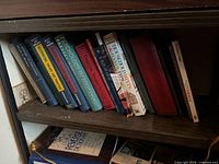 Shelf with assorted hardcovers including Accounting Theory and Practice and Psychology in Action volumes plus additional educational and reference titles
