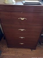 Front view of brown 4-drawer dresser with brass-tone handles