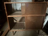 Front view of wood and rattan cabinet showing sliding doors and open shelves