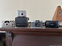 Front view showing five cameras on wooden surface